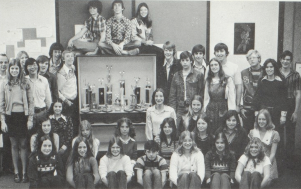 Black and white photo of Ron Underwood with the Beyer High School speech and debate team in 1975, surrounded by students and trophies celebrating their competitive success.
